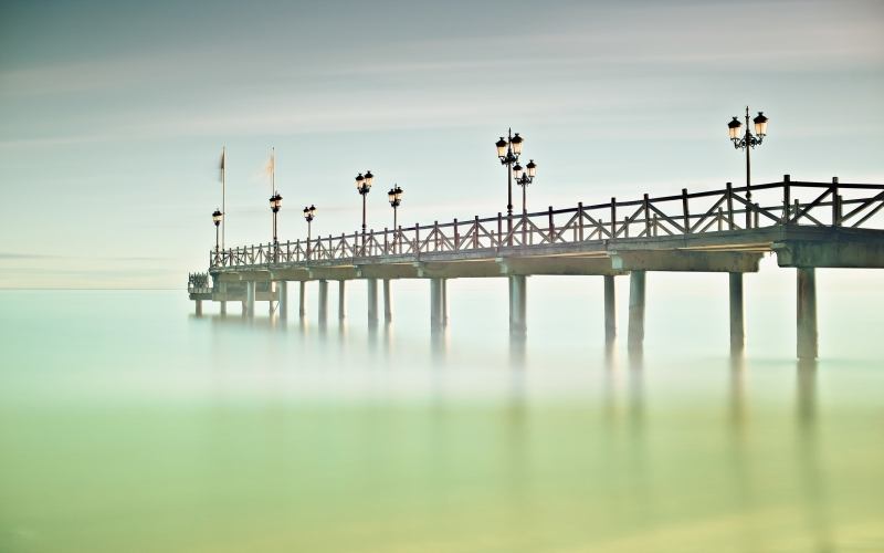 photo jetée en bois sur plage mer brumeuse